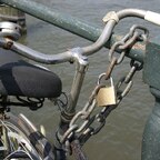 Mit Kette und Vorhängeschloss an einem Pfosten gesichertes Zweirad
